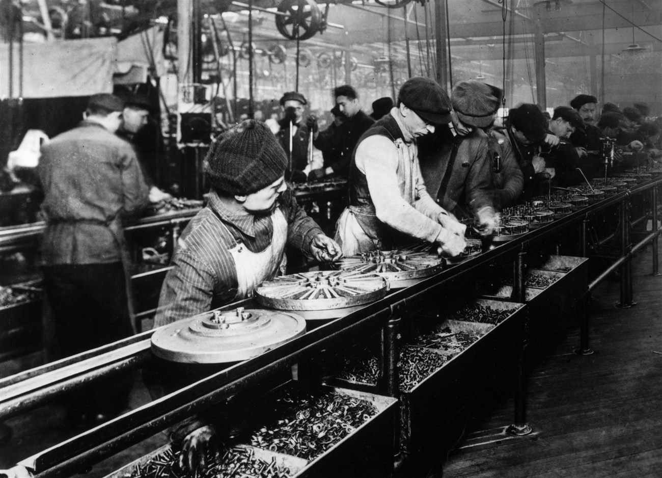 A linha de montagem móvel da Ford em 1913, com operários montando chassis do Model T em sequência.