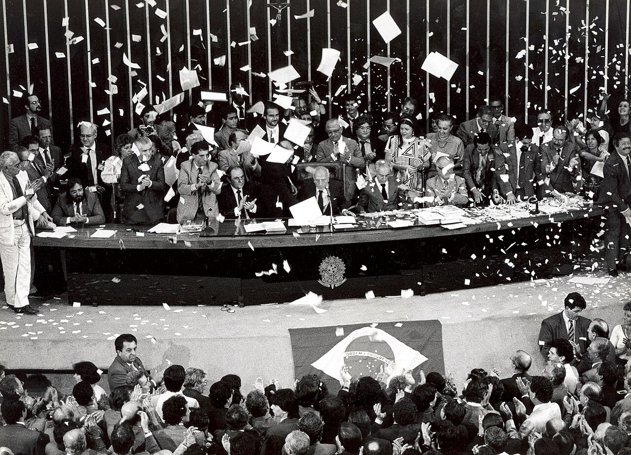 Promulgação da Constituição de 1988, com Ulysses Guimarães erguendo o texto sob chuva de papel picado.